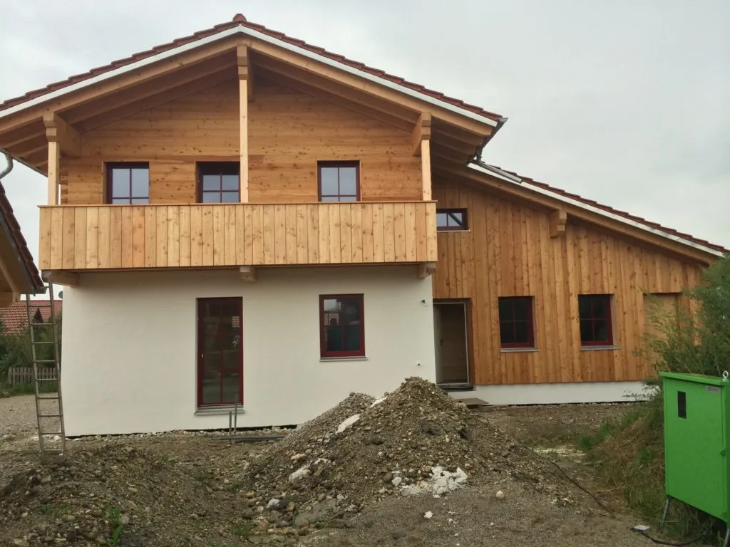 Haus mit senkrechter Holzverschalung im Obergeschoss und hölzernem Balkon