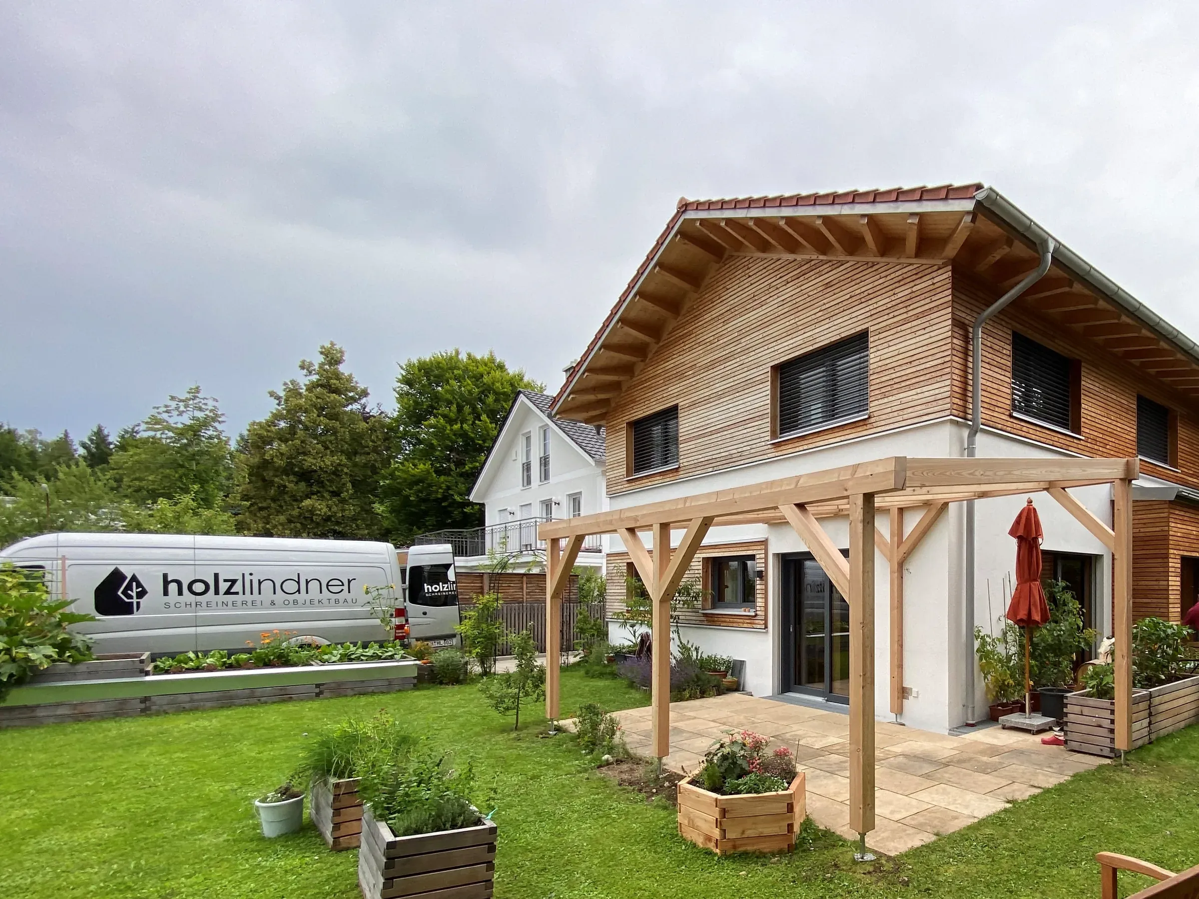 Wohnhaus mit waagerechter Holzschalung im Obergeschoss und Holzpergola über der Terrasse